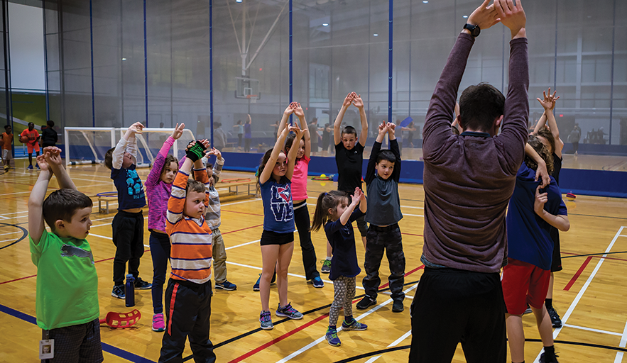 Abilities Centre Sport and Recreation coordinator leads young boys and girls through stretching exercise