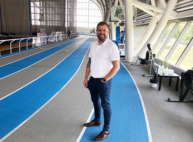Stuart McReynolds stands towards the camera on Abilities Centre's indoor track