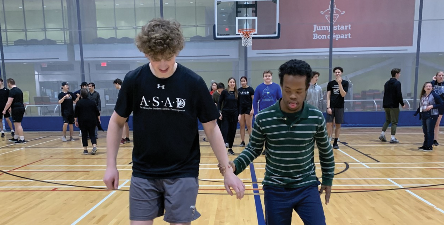 ASAD student athlete assisting a Thrive student share Abilities Centre court with fitness activity