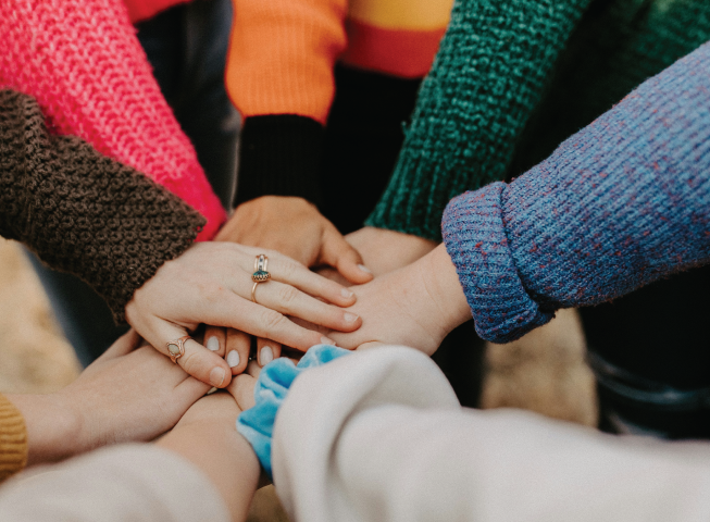 a group of people put their hands in a circle 