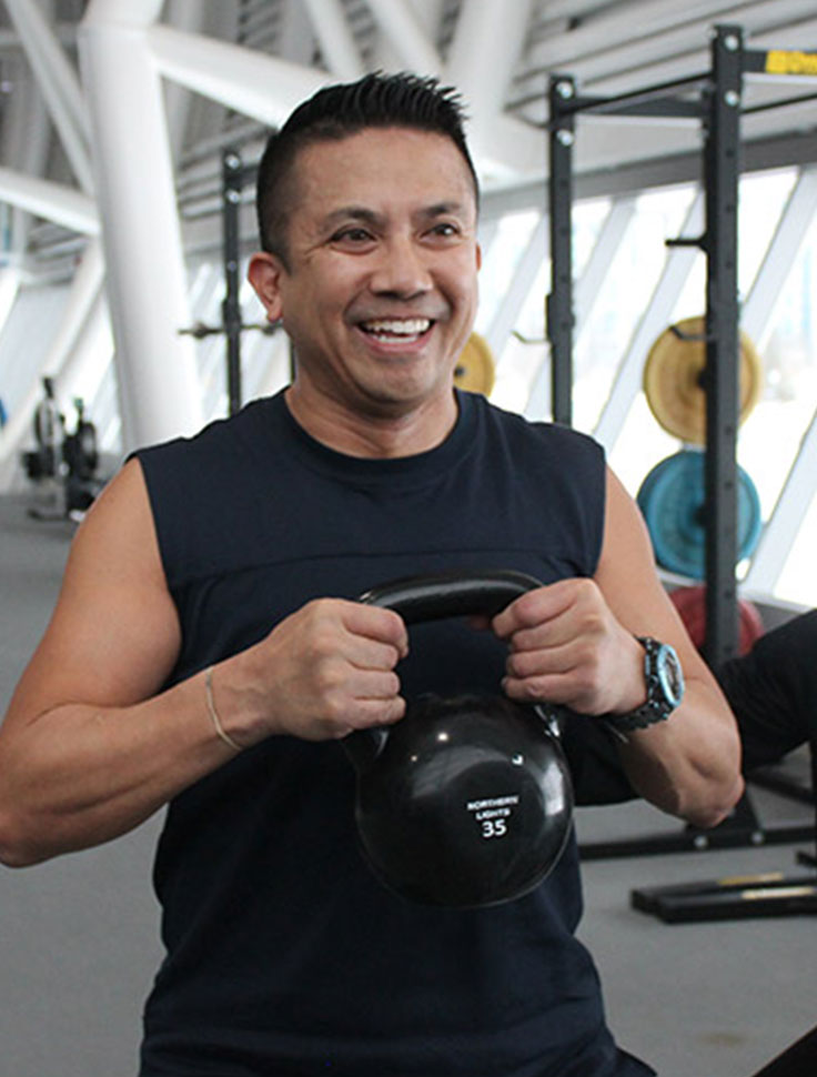 a person holding a kettle bell smiling and working out
