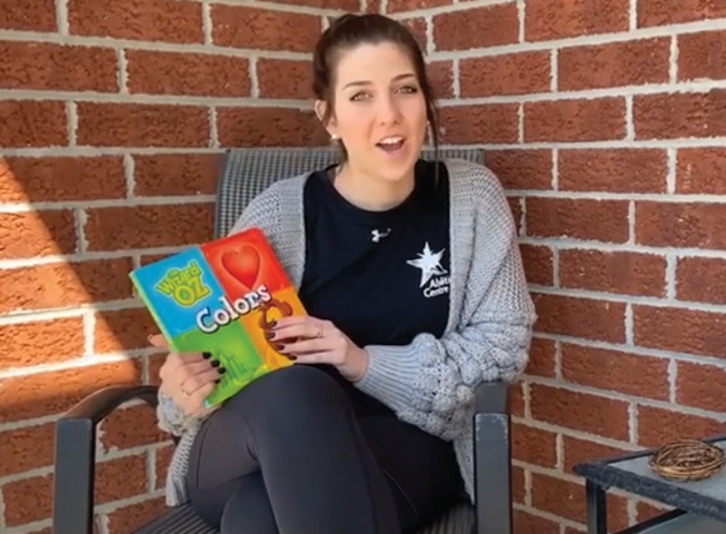 Victoria, an Abilities Centre staff member, sits on her front porch outside holding The Wizard of Oz Colours 