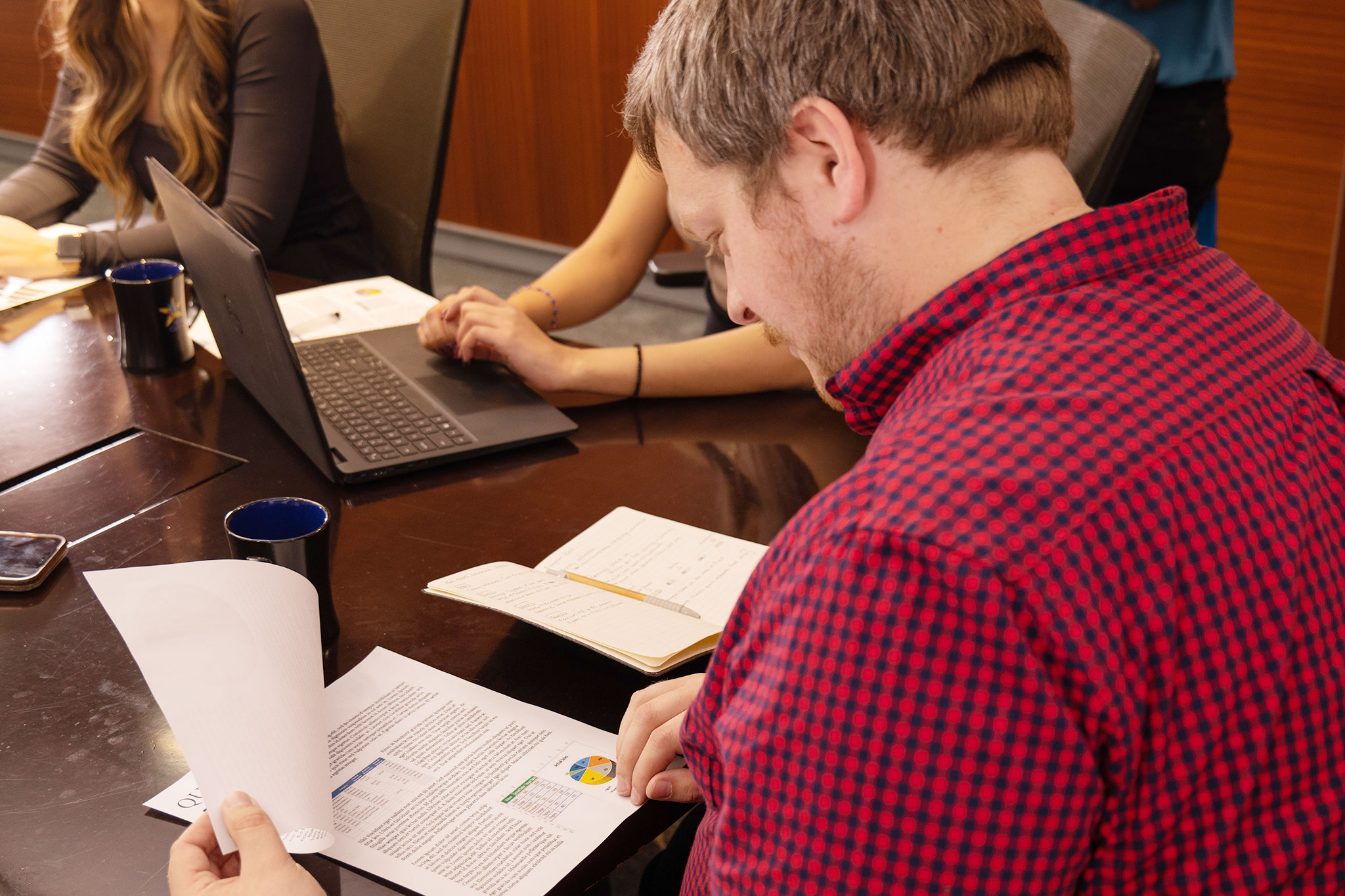 people looking at reports sitting around the board room table 