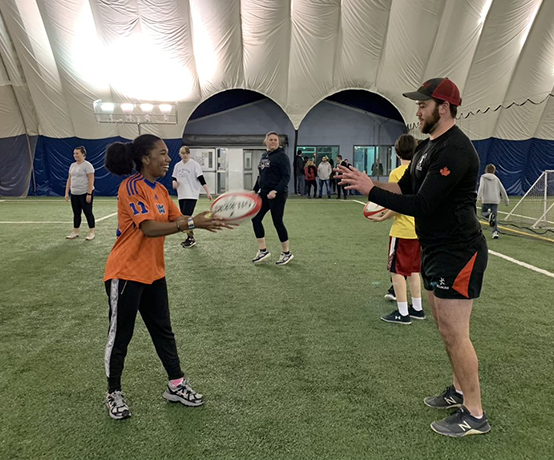 Abilities Centre coordinators and participants play a game of Mixed Ability Rugby on a turfed surface