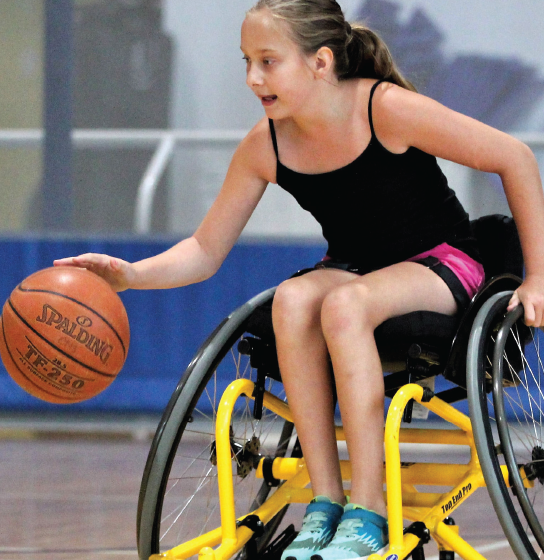a young girl racing up the court playing wheelchair basketball