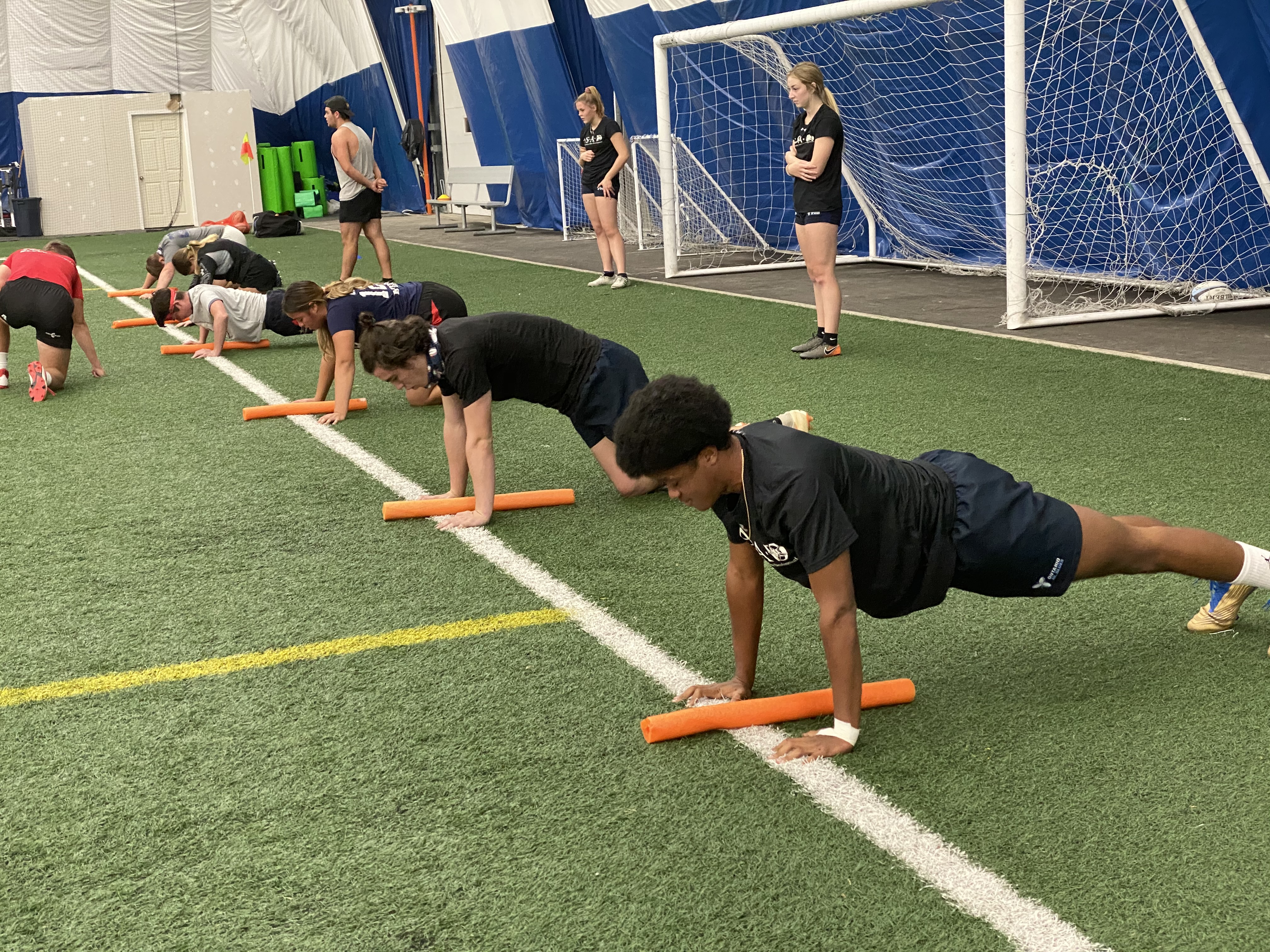 ASAD student doing plank postion lined up on indoor field