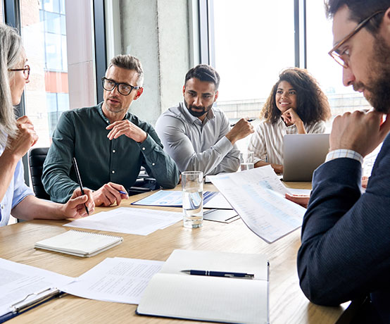 people sit at a long table in a meeting 