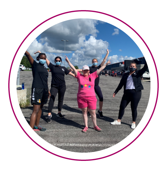 Abilities Centre Staff and participants pose in the parking lot arms in the air celebrating the end of a great program