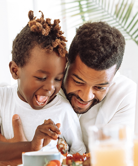 a father and son share a smile while playing at the kitchen table