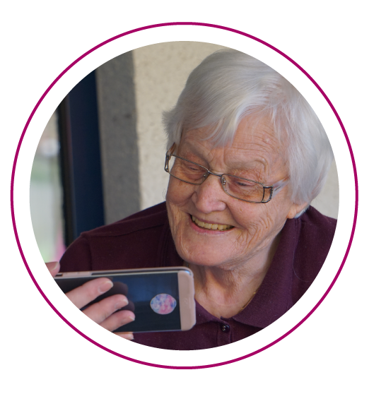 a senior woman smiles as she looks at her phone 
