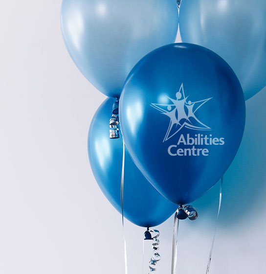 Blue Balloons float through the air with Abilities Centre logo on them. 