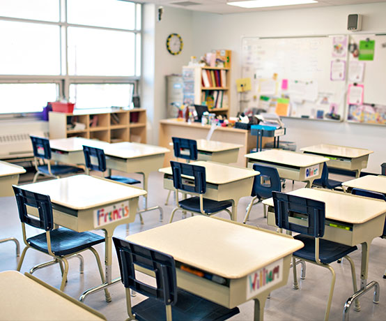 A class room full of desks facing a white board