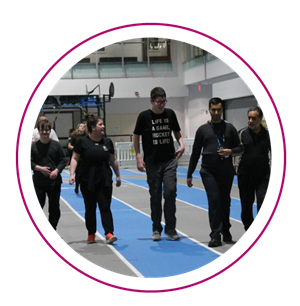 5 participants chatting and laughing as they walk Abilities Centre's indoor track