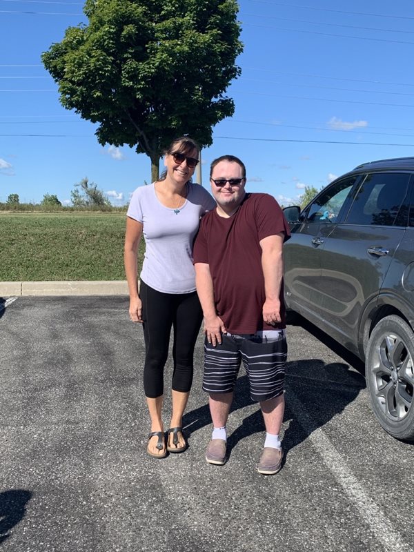 Thrive participant Ben (left) takes a photo with his mom while in a parking lot program at Abilities Centre