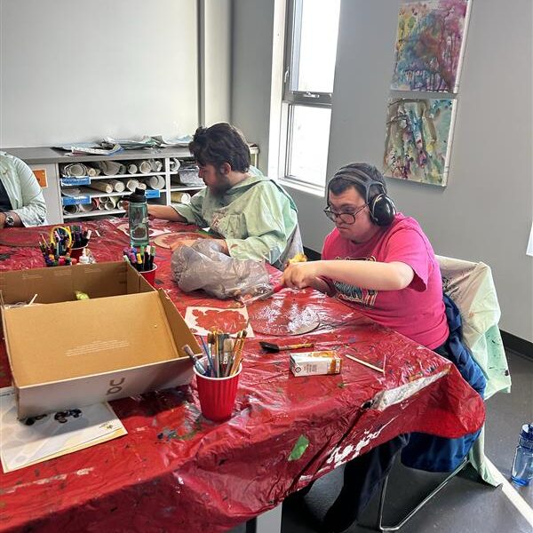 Two participants sit at a table while painting.