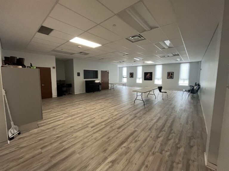 An open room with a table in the middle and four tall windows.