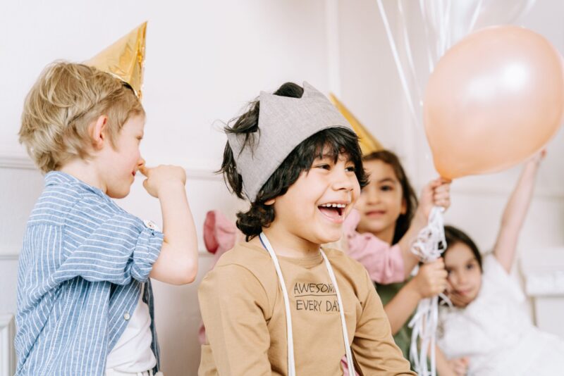 A boy wearing a crown smiles at his birthday party.