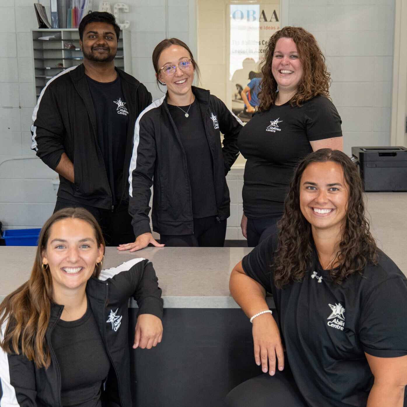A group of personal trainers smile as they pose together.