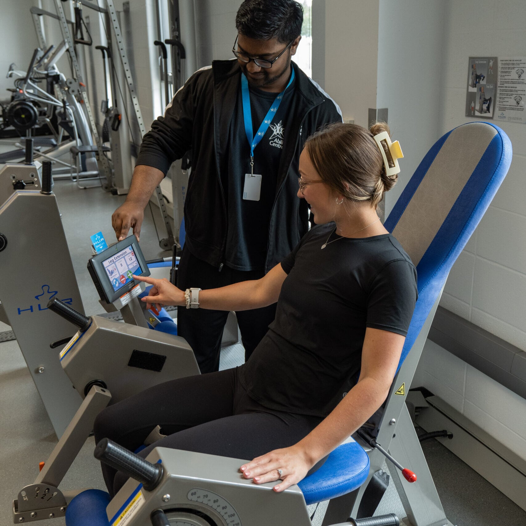 A trainer showing a woman how to use a H.U.R. machine.