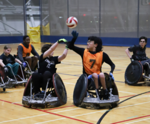 Two people face off for the ball during a game of wheelchair rugby.